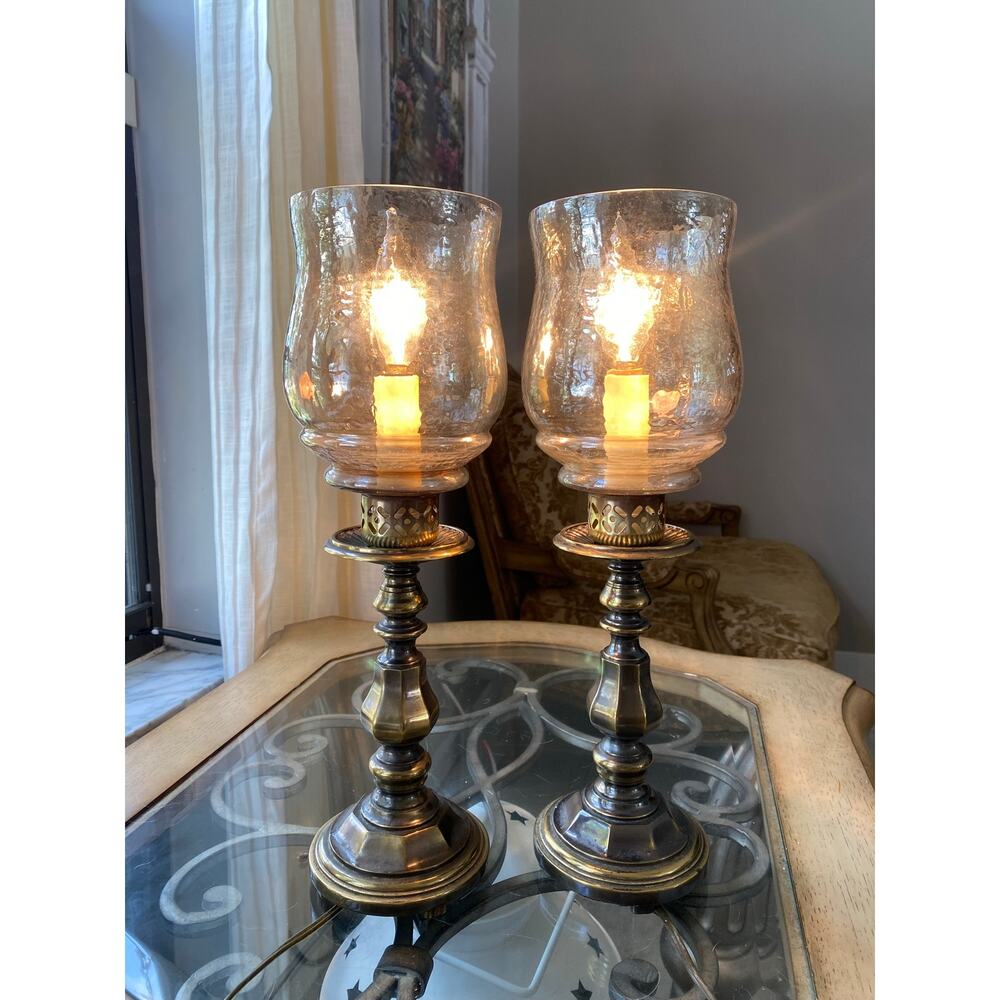 pair of vintage brass hurricane lamps featuring seeded glass shades.